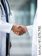 Two unidentified doctors in white coats greet each other in the corridor. Generated by AI. Стоковое AI-изображение, AI-художник Ярославский Максим / Фотобанк Лори