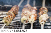 Closeup image of cooking delicious barbecue, shish kebabs with onion on the grill with coals. Appetizing pieces of meat are fried on metal skewers. Holidays in the nature. Tasty picnic in forest. Стоковое фото, фотограф YuryKara / Фотобанк Лори