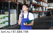 In warehouse of store, guy checks quantity of goods and receipt documents for products. Стоковое видео, видеограф Яков Филимонов / Фотобанк Лори