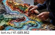 Geographer exploring the terrain on the model. Стоковое AI-изображение, AI-художник Кирилл Черезов / Фотобанк Лори