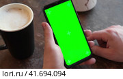 Man Use of Mobile Phone with Blank Green Screen in a Cafe on Rustic Vintage Wooden Table. Male Holding Smart Phone Empty ChromaKey Screen Mock up in Coffee Shop. Morning. Showing Mock up Video Footage. Стоковое видео, видеограф Марина Демидюк / Фотобанк Лори