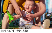 Little baby learns to play with sand in a children's sandbox under the control of a mother woman. Kid aged one year. Стоковое видео, видеограф Андрей Журавлев / Фотобанк Лори