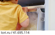 Baby takes a risk and opens the freezer door to grab some ice cream. Always make sure to close the fridge door properly to avoid any accidents Kid aged about two years (one year ten months) Стоковое видео, видеограф Андрей Журавлев / Фотобанк Лори