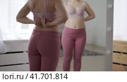 A woman tries on a bra in the fitting room, a bustier with a wide clasp is reflected in the mirror. Стоковое видео, видеограф Станислав Тарко / Фотобанк Лори