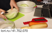 The man includes a video with a step -by -step recipe on a laptop. He cuts cabbage. Preparing sauerkraut at home. Стоковое видео, видеограф Vadzim Yakubovich / Фотобанк Лори