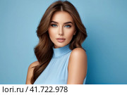 Close-up portrait of beautiful sensual caucasian woman with brown hair wearing blue clothes on a blue background.. AI. Стоковое AI-изображение, AI-художник Sergey Grishin / Фотобанк Лори