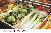 Seasonal leeks, carrots, cabbage are laid out in separate containers on grocery store window. Стоковое видео, видеограф Яков Филимонов / Фотобанк Лори