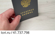 Мужская рука держит трудовую книжку гражданина Российской Федерации с трудовым стажем и нетерпеливо постукивает ею по столу в ожидании. Стоковое видео, видеограф Sergei Gorin / Фотобанк Лори