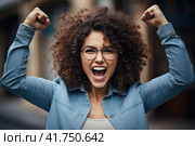 A young girl with curly hair rejoices in luck with her fists raised up. Generated by AI. Стоковое AI-изображение, AI-художник Ярославский Максим / Фотобанк Лори