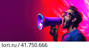 A young enraged man shouts violently into a megaphone. Purple-blue smoke on the background. Generated by AI. Стоковое AI-изображение, AI-художник Ярославский Максим / Фотобанк Лори