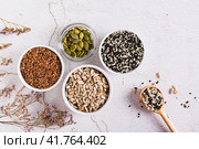 Sesame, flax, pumpkin and sunflower seeds in bowls and spoon for women's health top view. Стоковое фото, фотограф Елена Руй / Фотобанк Лори