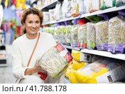 Woman take hay from shelf, inspect label in pet store. Стоковое фото, фотограф Яков Филимонов / Фотобанк Лори