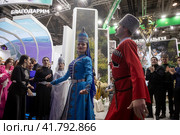 Люди в национальных костюмах танцуют у стенда Республики Адыгея на Международной выставке-форуме "Россия" на территории выставочного комплекса ВДНХ в городе Москве, Россия (2023 год). Редакционное фото, фотограф Николай Винокуров / Фотобанк Лори