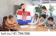 Group of curious preteen learners and young female teacher with flag of Croatia in schoolroom of academy. Стоковое видео, видеограф Яков Филимонов / Фотобанк Лори