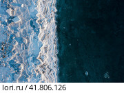 Вид сверху на обледеневший берег моря. Зимняя аэрофотосъёмка морского побережья. Лёд, льдины и замерзающая морская вода. Природа Крайнего Севера. Холодная зимняя погода. Суровый арктический климат. Красивый ледяной фон. Побережье Охотского моря. Стоковое фото, фотограф Андрей Степанов / Фотобанк Лори