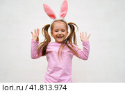 A funny laughing child in the guise of a rabbit on white bacground. The year according to the zodiac sign of the Eastern calendar. Easter Greeting poster. Стоковое фото, фотограф Ирина Старикова / Фотобанк Лори