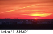 Sunset in a haze of thick clouds over the houses in the urban landscape, time lapse. Evening sun in continuous cloudiness on a hot foggy sky above the silhouettes of city buildings, timelapse. Стоковое видео, видеограф Андрей Журавлев / Фотобанк Лори