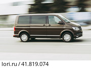 Fast moving Volkswagen Transporter T6 on the city road. Brown minivan rides on street. Commercial auto in fast motion with blurred background. speeding in the city concept (2021 год). Редакционное фото, фотограф Константин Григорьев / Фотобанк Лори