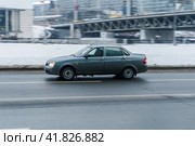 Car Lada Priora is driving through the city on wet slippery road. Fast moving gray sedan auto on Moscow winter streets. Редакционное фото, фотограф Константин Григорьев / Фотобанк Лори