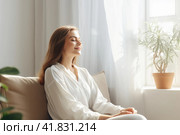 A seated young woman relaxes on the sofa. Стоковое AI-изображение, AI-художник Татьяна  Бральнина / Фотобанк Лори