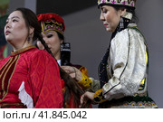 Невесте после свадьбы женщины расплетают девичьи косы и готовят невесту к замужеству во время свадебного обряда по калмыцким традициям на выставке-форуме "Россия" на ВДНХ в городе Москве, Россия (2023 год). Редакционное фото, фотограф Николай Винокуров / Фотобанк Лори