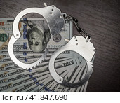 one hundred dollar bills and steel handcuffs close up. Стоковое фото, фотограф Артем Курутин / Фотобанк Лори