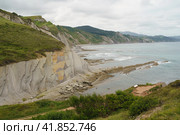 The seascape in Basque Autonomous Community in summer cloudy day. Wide Atlantic ocean beach surrounded by mountains at low tide in Bay of Biscay. Charming Zumaia Algorri beach. Стоковое фото, фотограф YuryKara / Фотобанк Лори