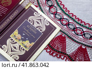 Крупным планом сборник стихов Сергея Есенин и михайловское кружево лежат на столе (2023 год). Редакционное фото, фотограф Николай Винокуров / Фотобанк Лори