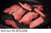 Frying Bacon Slices in a Pan. Crispy Pieces of Delicious Red Thin Smokey Bacon Fried in a Hot Skillet. Traditional Breakfast. Smoked Bacon Rasher or Strip Being Cooked. Grill. Fat High Calorie Food. Стоковое видео, видеограф Марина Демидюк / Фотобанк Лори
