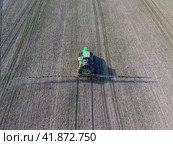 Tractor with hinged system of spraying pesticides. Fertilizing with a tractor, in the form of an aerosol, on the field of winter wheat. Стоковое фото, фотограф Леонид Еремейчук / Фотобанк Лори