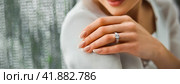 Woman Flaunting Her Elegant Diamond Engagement Ring. Close-up of a woman's hand as she shows off a sparkling diamond ring, symbolizing engagement. Стоковое AI-изображение, AI-художник Igor Tichonow / Фотобанк Лори