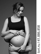 Black and white photo of man behind female and hugs her pregnant exposed belly. Стоковое фото, фотограф Сергей Пристяжнюк (Serg Zastavkin) / Фотобанк Лори