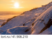 Winter arctic landscape. View from the snow-covered rocky slope of the mountain at a beautiful sunrise over the tundra. Cold windy and frosty weather. Chukotka, Siberia, Russia. Shallow depth of field. Стоковое фото, фотограф Андрей Степанов / Фотобанк Лори