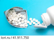 A white jar with pills lies on a blue background. Next to it is a bag made of a hundred dollar bill. Стоковое фото, фотограф Ярославский Максим / Фотобанк Лори