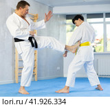 Underage boy and middle-aged man performing karate techniques in pair. Стоковое фото, фотограф Яков Филимонов / Фотобанк Лори