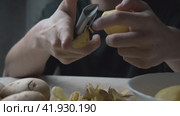 Men's hands peel potatoes at the kitchen table. A cinematic picture. Стоковое видео, видеограф Ярославский Максим / Фотобанк Лори