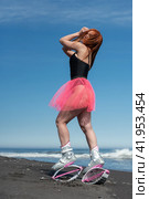 Woman athlete in sports Kangoo Jumps boots, black swimsuit and short skirt posing on beach during outdoors fitness workout on seashore (2022 год). Редакционное фото, фотограф А. А. Пирагис / Фотобанк Лори