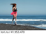 Athletic woman in Kangoo Jumps boots, one piece swimsuit and short pink skirt running and jumping on beach during fitness and aerobic exercising outdoors (2022 год). Редакционное фото, фотограф А. А. Пирагис / Фотобанк Лори
