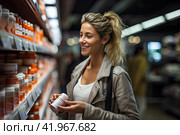 A young beautiful girl stands in front of a refrigerator shelf in a supermarket and chooses breakfast products. Healthy lifestyle. Стоковое AI-изображение, AI-художник Ярославский Максим / Фотобанк Лори