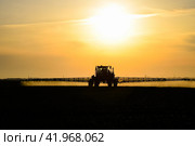 tractor with the help of a sprayer sprays liquid fertilizers on young wheat in the field. Стоковое фото, фотограф Леонид Еремейчук / Фотобанк Лори