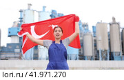 Sad young woman worker standing with big flag of Turkey against background of factory. Стоковое видео, видеограф Яков Филимонов / Фотобанк Лори