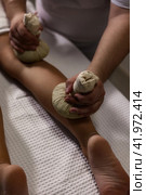 Masseur doing spa massage of leg with herbal compresses bag Thai method. Close up of relaxing massage for woman at spa salon, wellness herbal massaging leg. Relax massage concept. Copy ad text space. Стоковое фото, фотограф Aleksandr Golubev / Фотобанк Лори