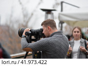 Фотограф на улице с фотографирует со штатива н телеобъектив (2019 год). Редакционное фото, фотограф Оксана / Фотобанк Лори