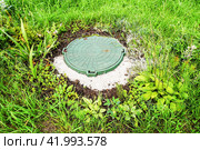 Covered sewer manhole with green plastic cover, sewage system. Sewerage networks. Sanitary sewer system manhole cover. Стоковое фото, фотограф FotograFF / Фотобанк Лори