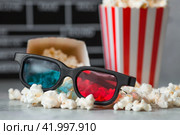 A banner for the film industry. A movie date. A movie camera, 3D glasses, popcorn in striped cups on a stylish concrete gray background. The premiere of the film. (2024 год). Стоковое фото, фотограф Photojuli / Фотобанк Лори