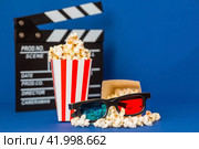 A banner for the film industry. A romantic movie date. A movie camera, 3D glasses, popcorn in striped cups on a blue background. The premiere of the film. (2024 год). Стоковое фото, фотограф Photojuli / Фотобанк Лори