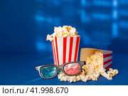 A banner for the film industry. A romantic movie date. A movie camera, 3D glasses, popcorn in striped cups on a blue background. The premiere of the film. (2024 год). Стоковое фото, фотограф Photojuli / Фотобанк Лори