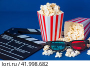 A banner for the film industry. A romantic movie date. A movie camera, 3D glasses, popcorn in striped cups on a blue background. The premiere of the film. (2024 год). Стоковое фото, фотограф Photojuli / Фотобанк Лори