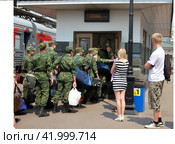 Парень и девушка смотрят как новобранцы в военной форме следуют к переходу на ЖД платформу к поезду (2012 год). Редакционное фото, фотограф Ольга Зражевская / Фотобанк Лори