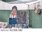 Senior saleswoman in Russian national clothes and kokoshnik in trade tent at Irbit fair, Russia (2023 год). Редакционное фото, фотограф Ирина Кононова / Фотобанк Лори